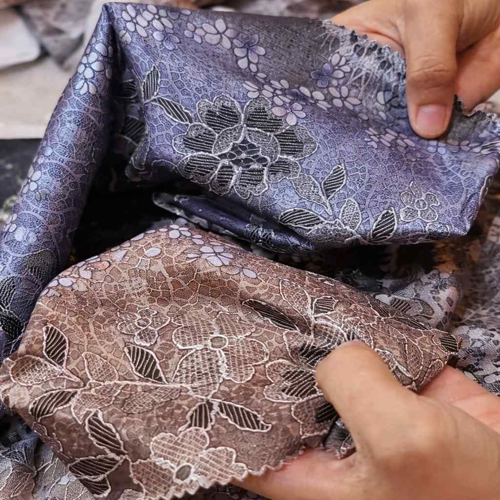 Kain lace dengan corak bunga yang halus dipegang untuk menunjukkan tekstur dan kualiti material