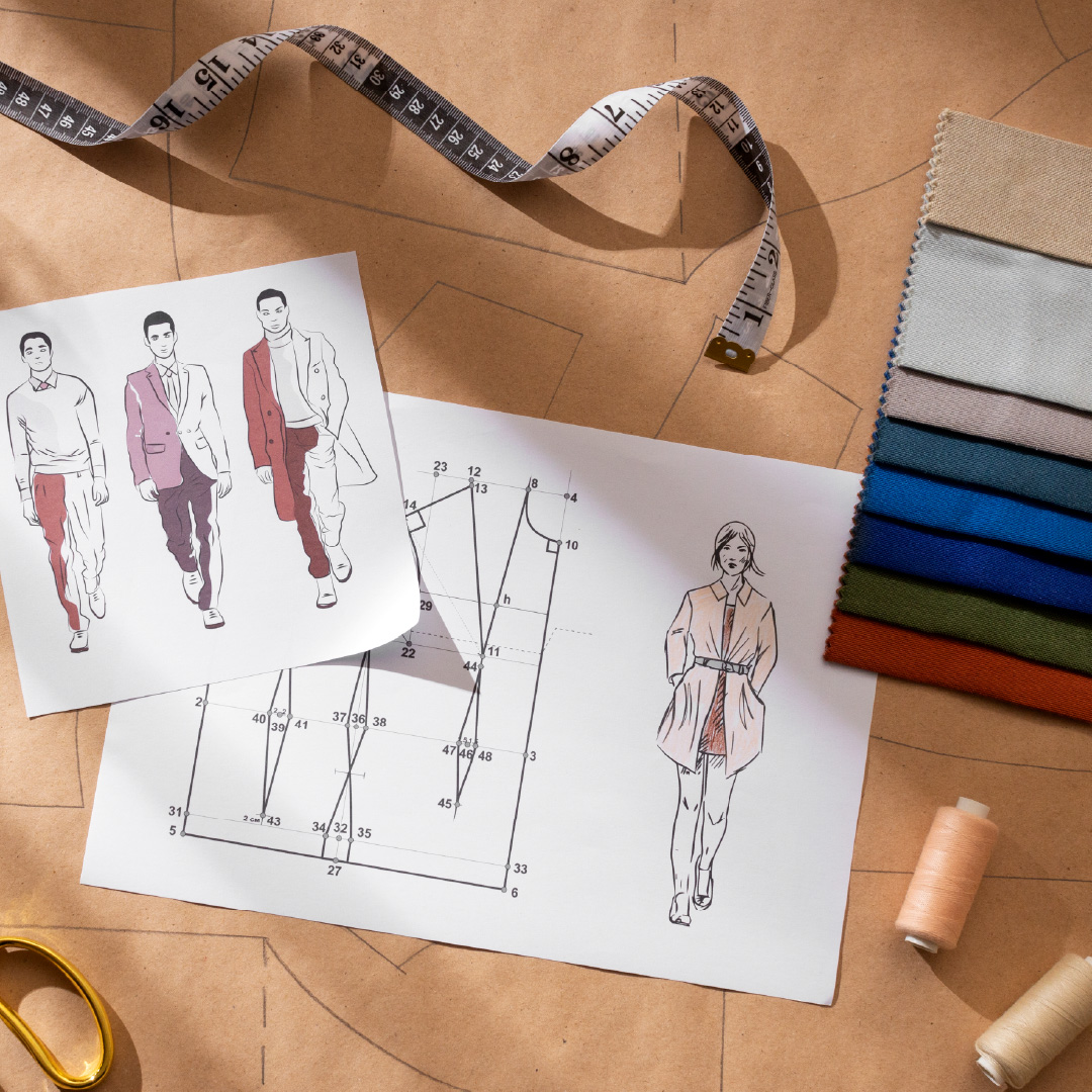 Lakaran design pakaian dan pola teknikal di atas meja bersama kain swatch dan pita ukur sebagai proses awal penyediaan mockup pakaian